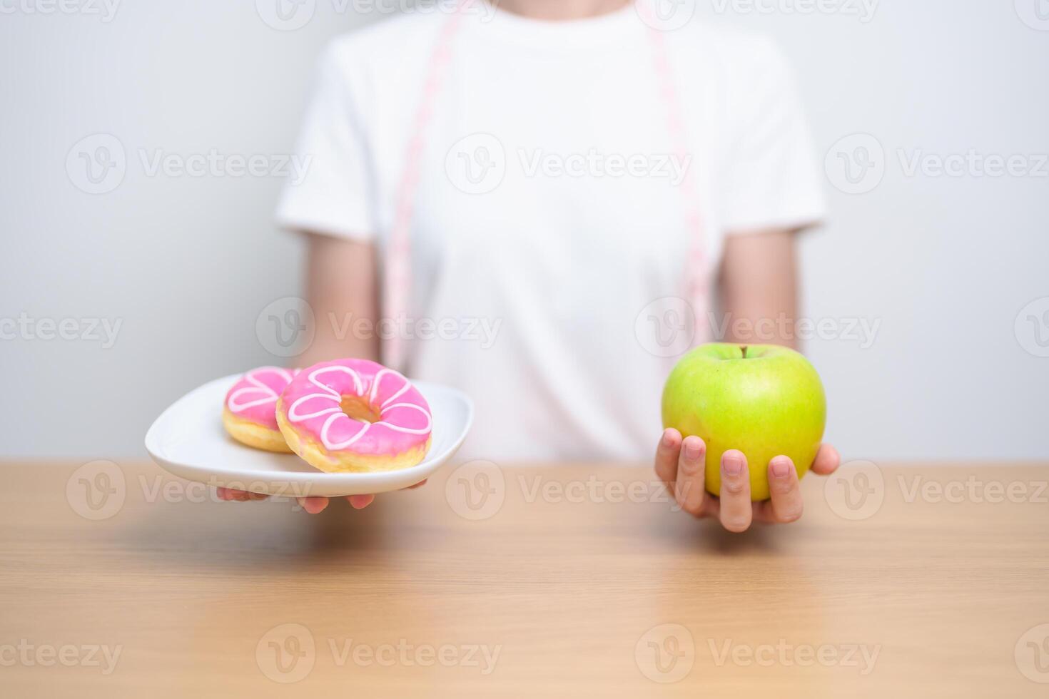 woman hand hold green Apple and donut, female fitness choose between fruit is Healthy and sweet is Unhealthy junk food. Dieting control, Weight loss, Obesity, eating lifestyle and nutrition concept photo