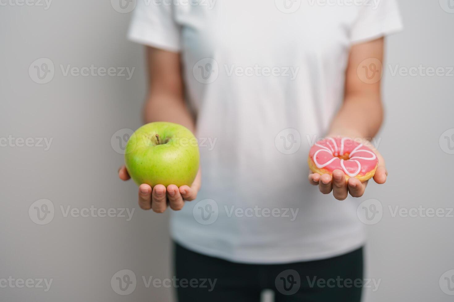 woman hand hold green Apple and donut, female fitness choose between fruit is Healthy and sweet is Unhealthy junk food. Dieting control, Weight loss, Obesity, eating lifestyle and nutrition concept photo