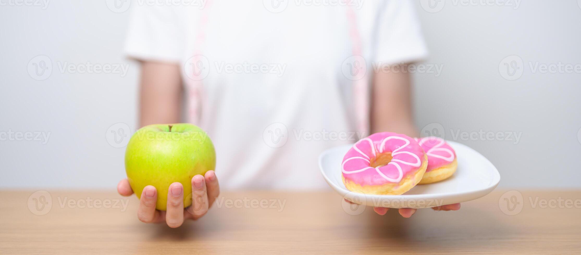 woman hand hold green Apple and donut, female fitness choose between fruit is Healthy and sweet is Unhealthy junk food. Dieting control, Weight loss, Obesity, eating lifestyle and nutrition concept photo