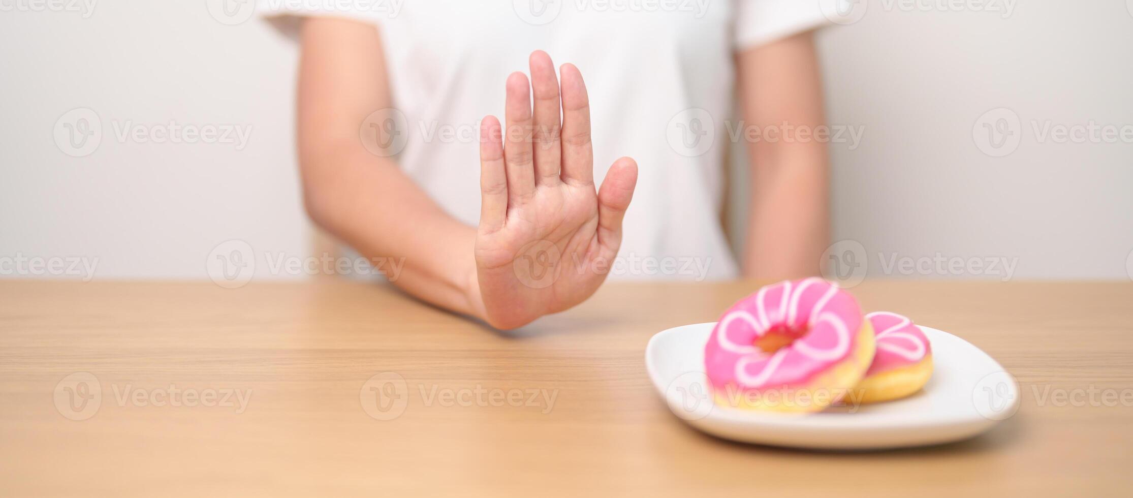 woman hand reject donut dessert, female refuse Unhealthy junk food. Dieting control, Weight loss, Obesity, eating lifestyle and nutrition concepts photo