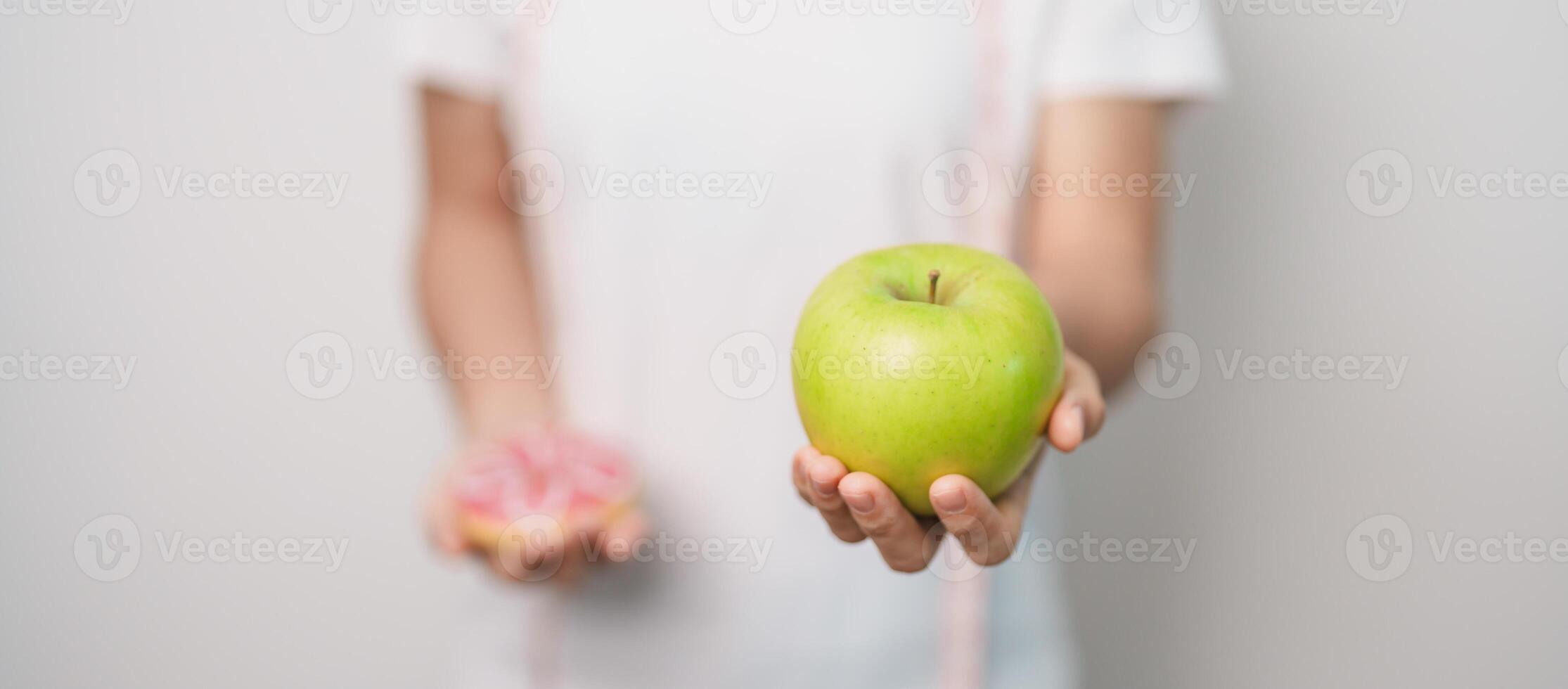 woman hand hold green Apple and donut, female fitness choose between fruit is Healthy and sweet is Unhealthy junk food. Dieting control, Weight loss, Obesity, eating lifestyle and nutrition concept photo