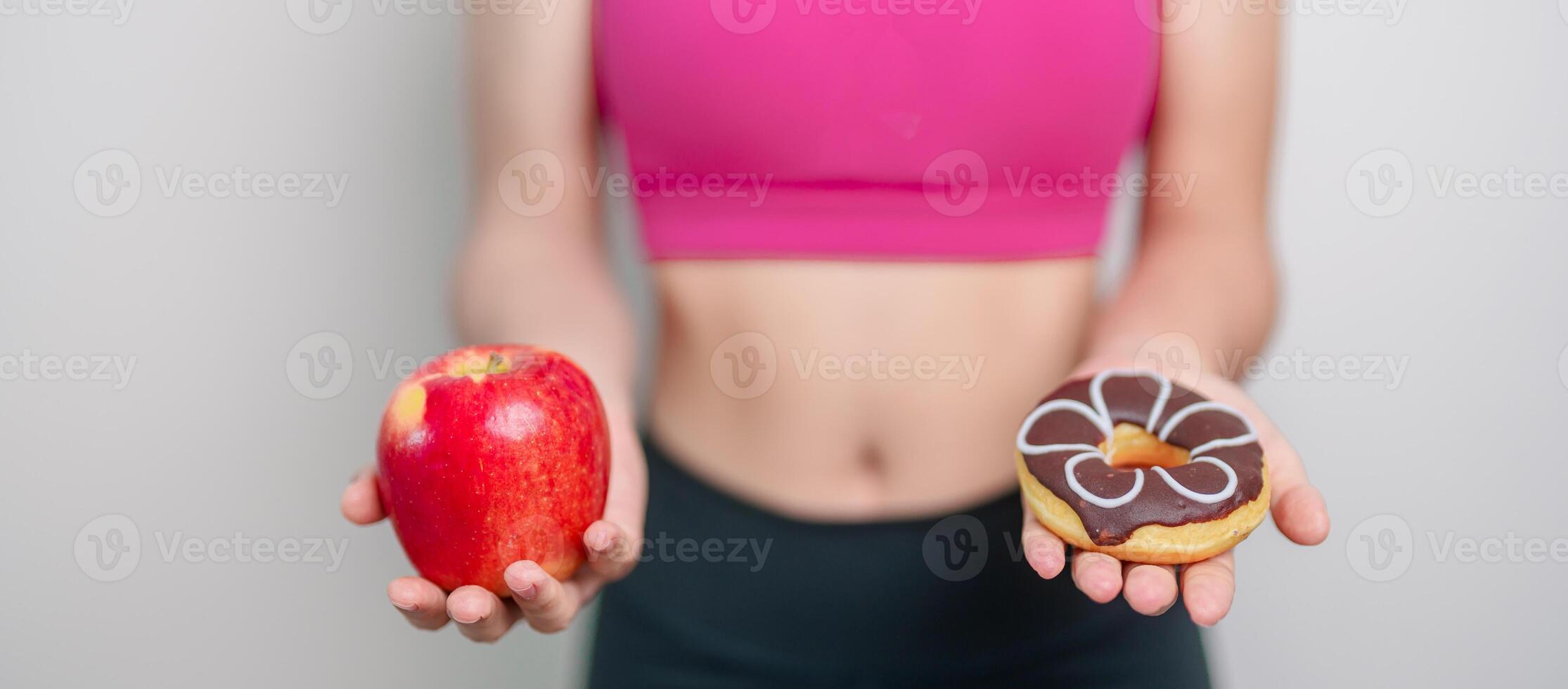 woman hand hold red Apple and donut, female fitness choose between fruit is Healthy and sweet is Unhealthy junk food. Dieting control, Weight loss, Obesity, eating lifestyle and nutrition concept photo