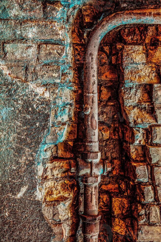 Old rusty water pipe in a brick wall. Old rusty pipe with valves on painted brick wall with rectangle recess. Urban build texture photo