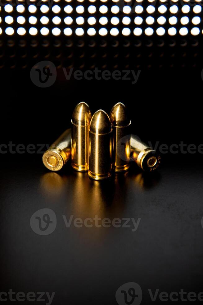 Pistol cartridges 9 mm on a smooth glossy surface with reflections. Ammunition for pistols and PCC carbines on a dark back. photo