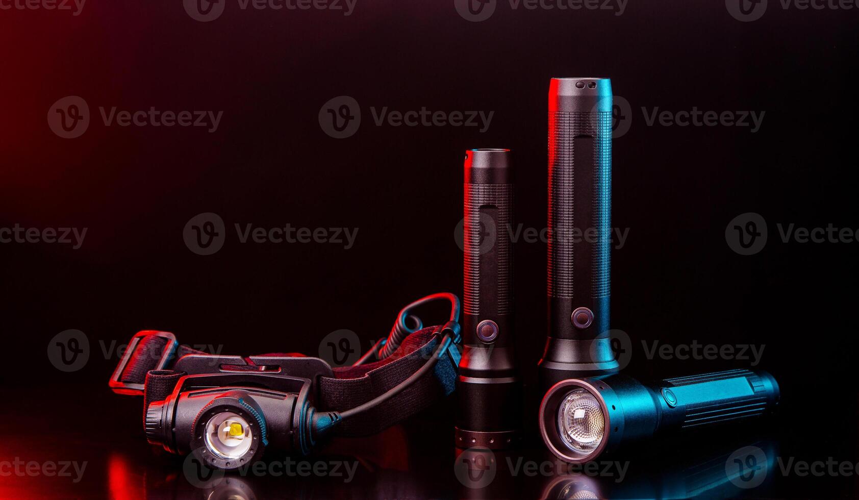 Head and pocket flashlights on a dark back. Modern lanterns illuminated with red-blue light. photo