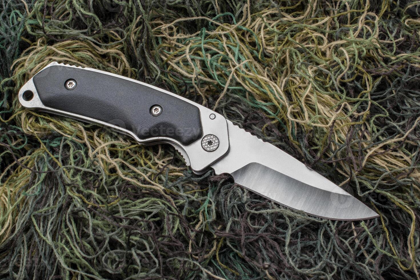 Folding penknife on the background of green threads. photo