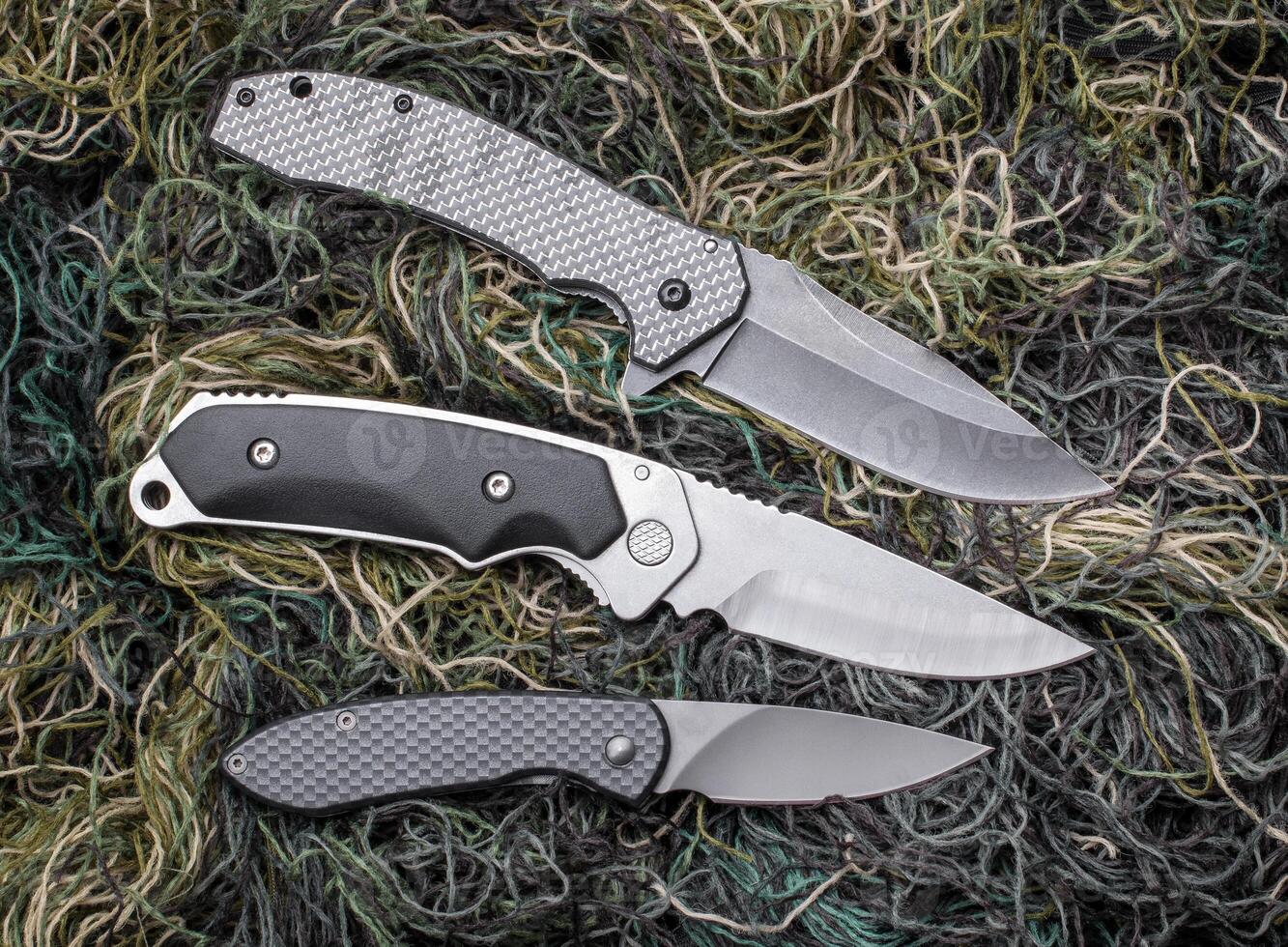 Folding pen knives on the background of green thread. photo