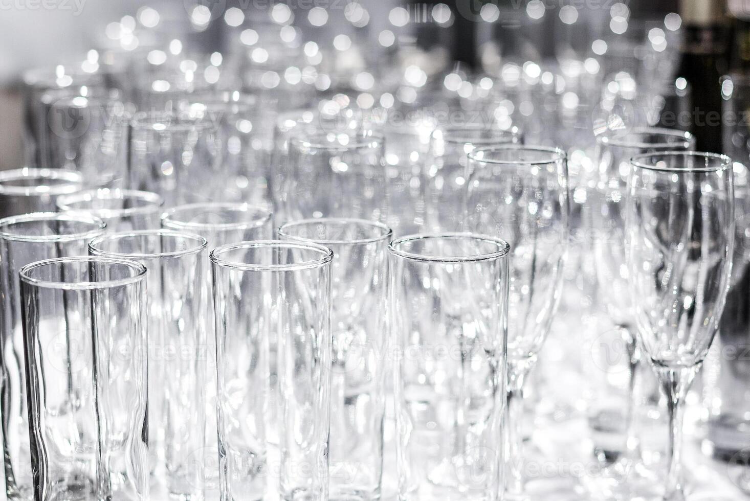 Lots of different empty glasses on the table. Preparing for a banquet, holiday or wedding. Blurred back. photo