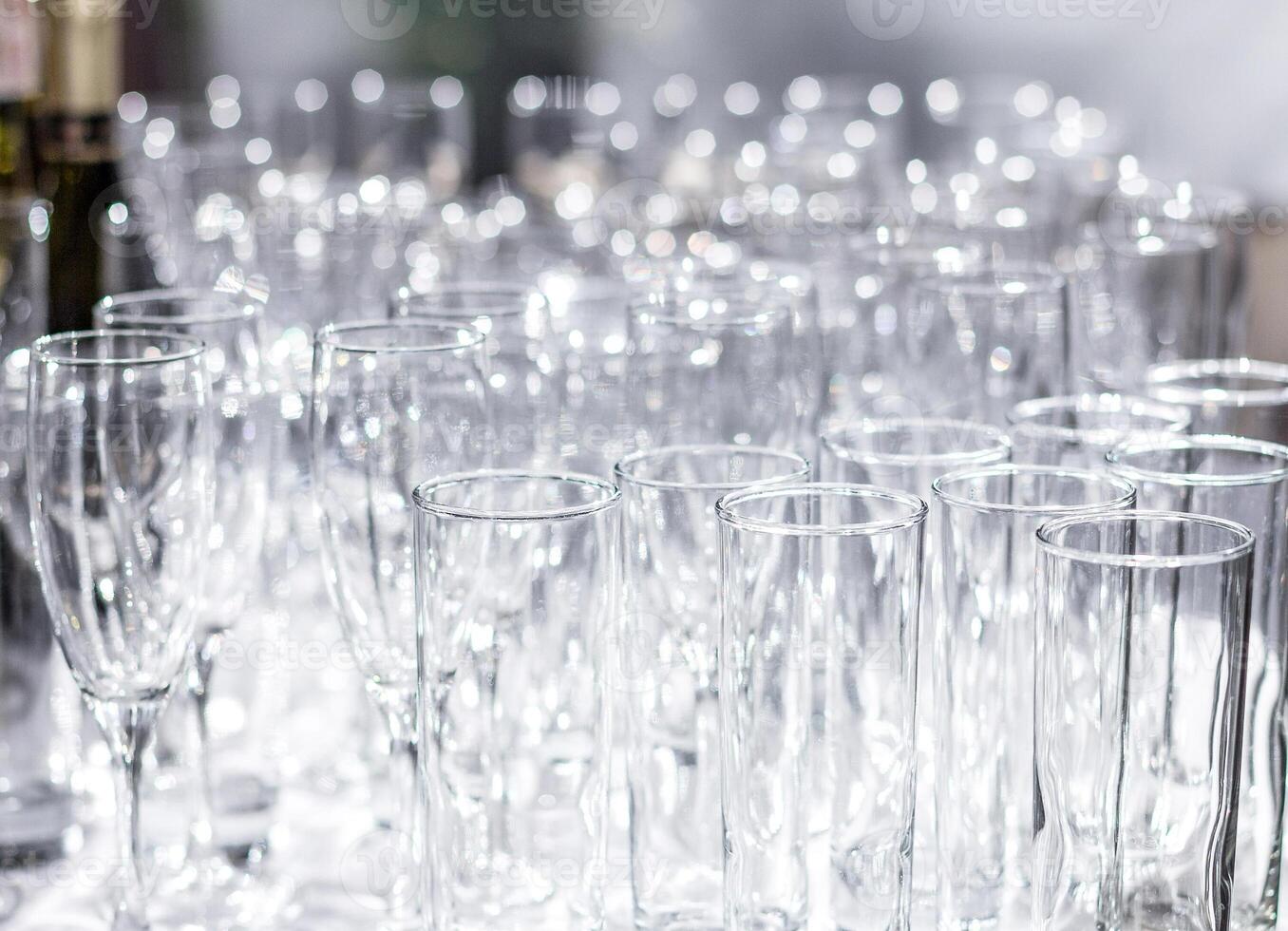Lots of different empty glasses on the table. Preparing for a banquet, holiday or wedding. Blurred back. photo