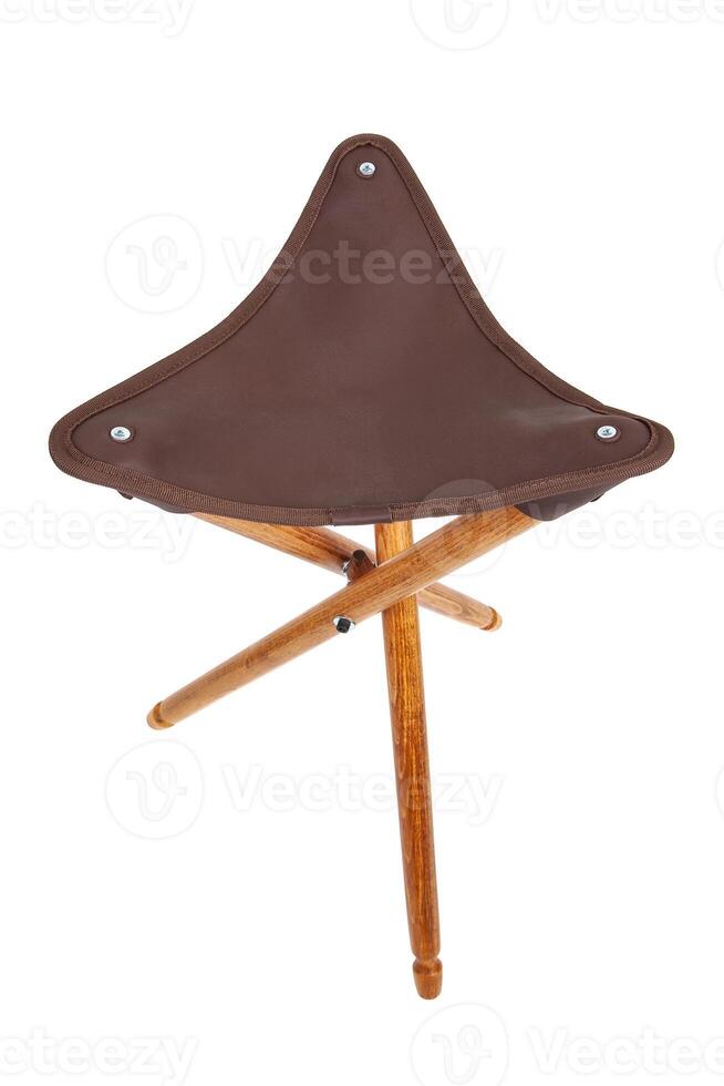 Folding wooden hunting stool tripod isolate on white background. Three-legged camping chair, Made of wood and leather. photo