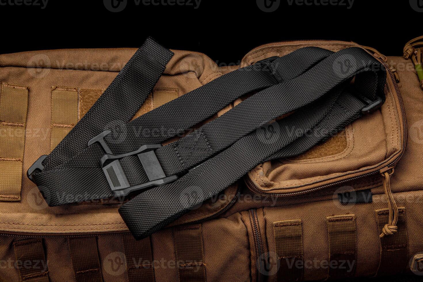 A black nylon weapon belt on a brown military backpack. Dark back. photo