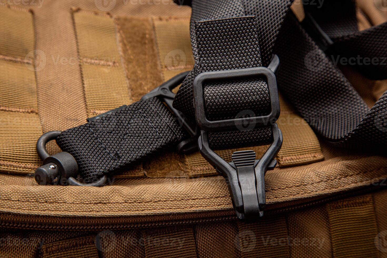 A black nylon weapon belt on a brown military backpack. Dark back. photo