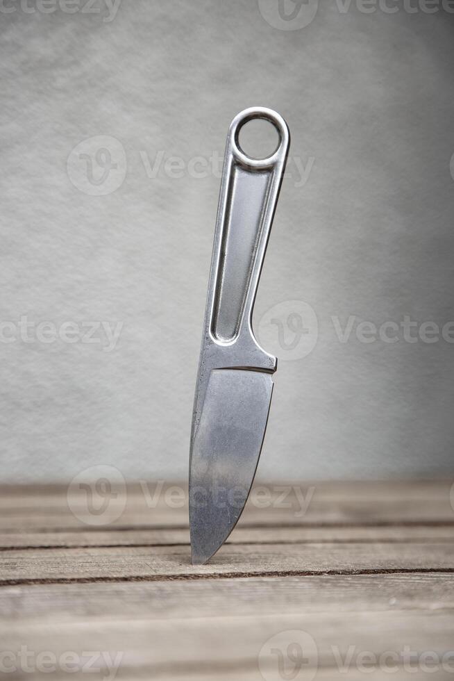 A knife with a metal handle made from a wrench. A tool weapon is stuck into a wooden surface. Light back. photo