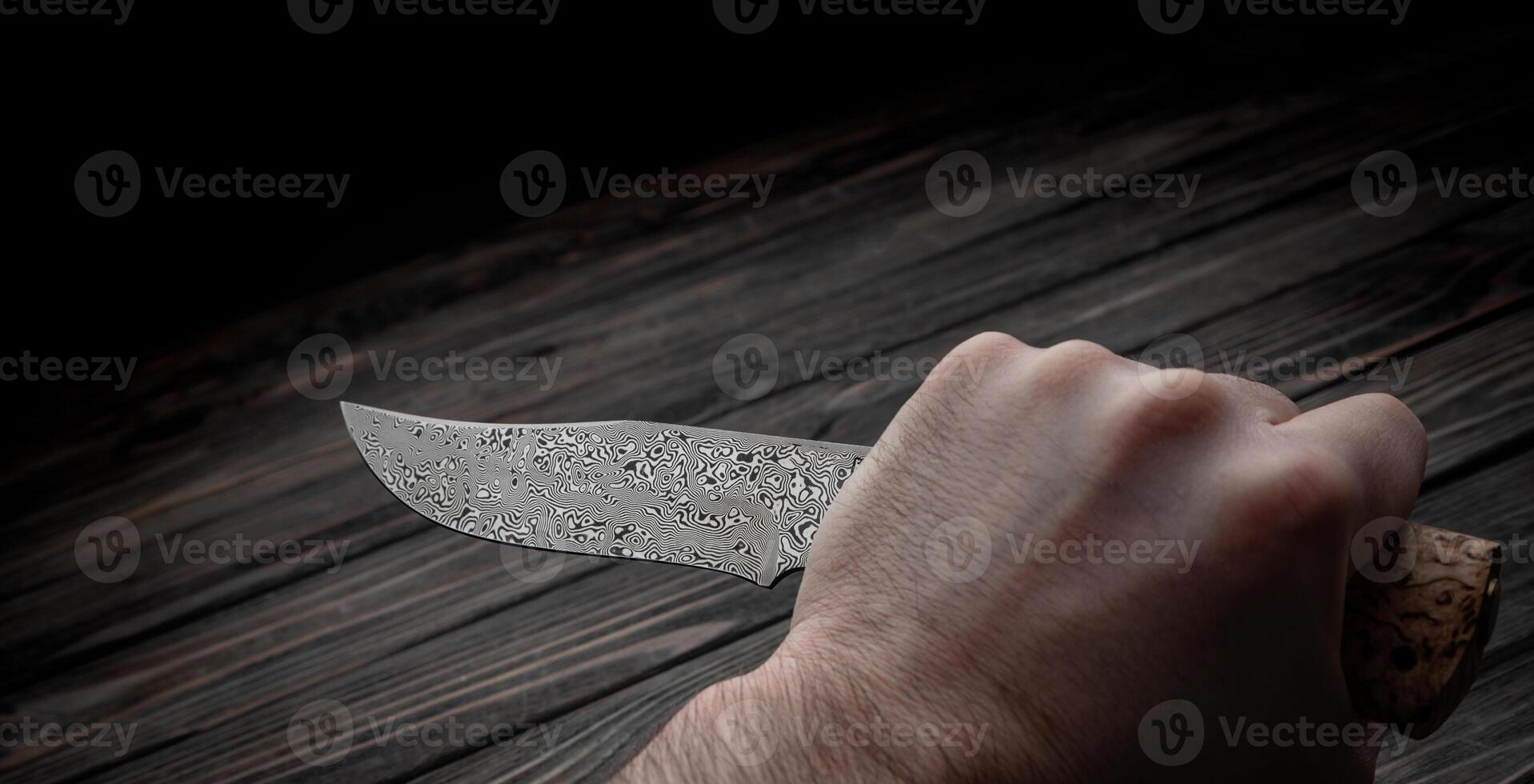 Hunting bowie knife with a wooden handle on dark wooden background. Steel arms weapon. top view photo