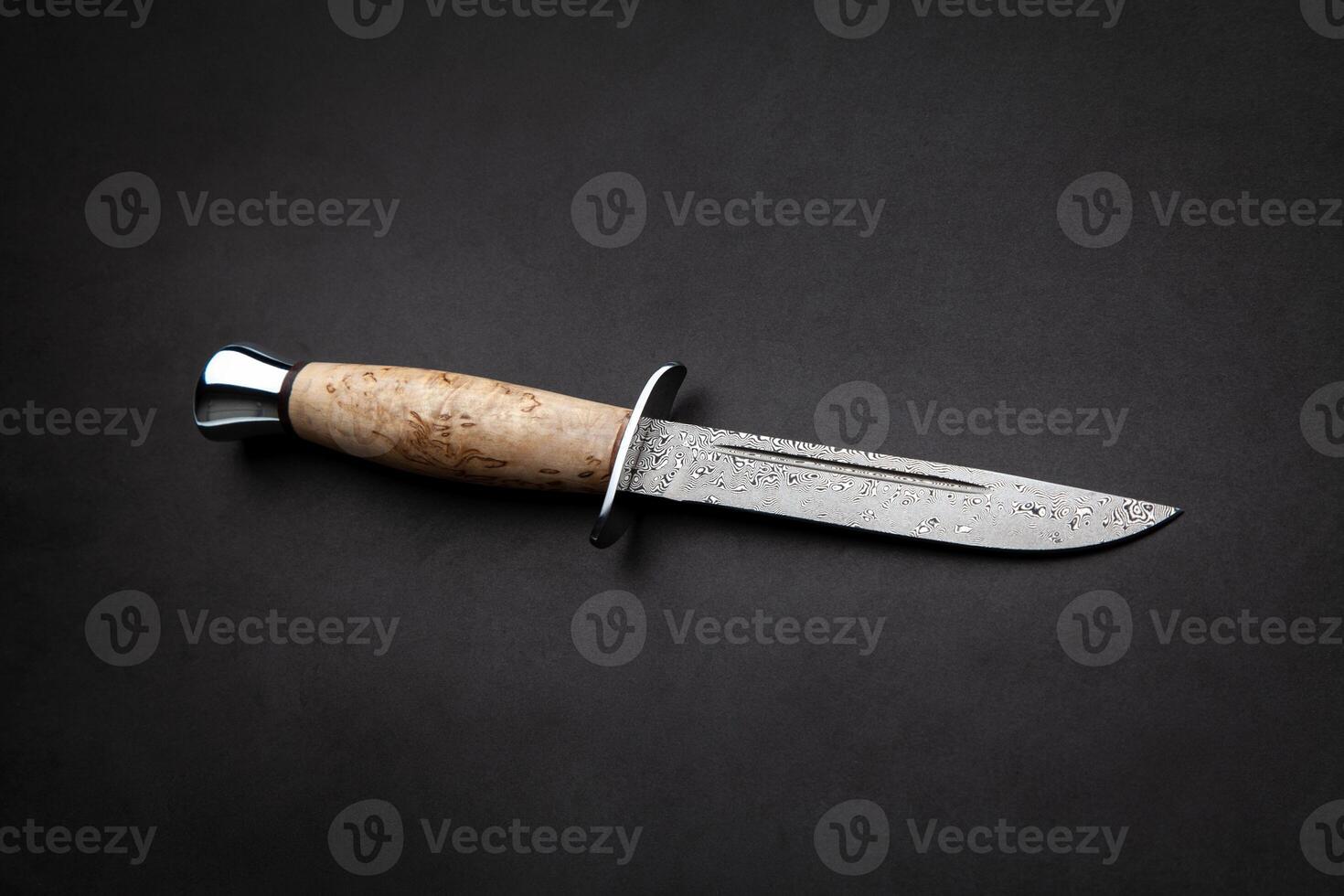Hunting knife with wooden handle on black back. photo