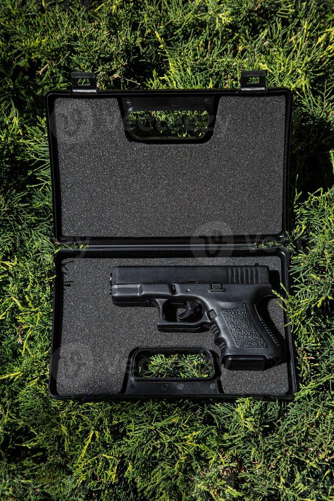 Modern semi-automatic pistol. Armament for the army and police. Short-barreled weapon. Green fir background. photo