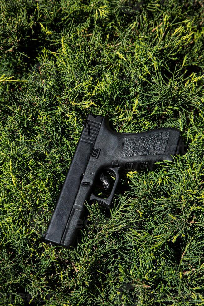 Modern semi-automatic pistol. Armament for the army and police. Short-barreled weapon. Green fir background. photo