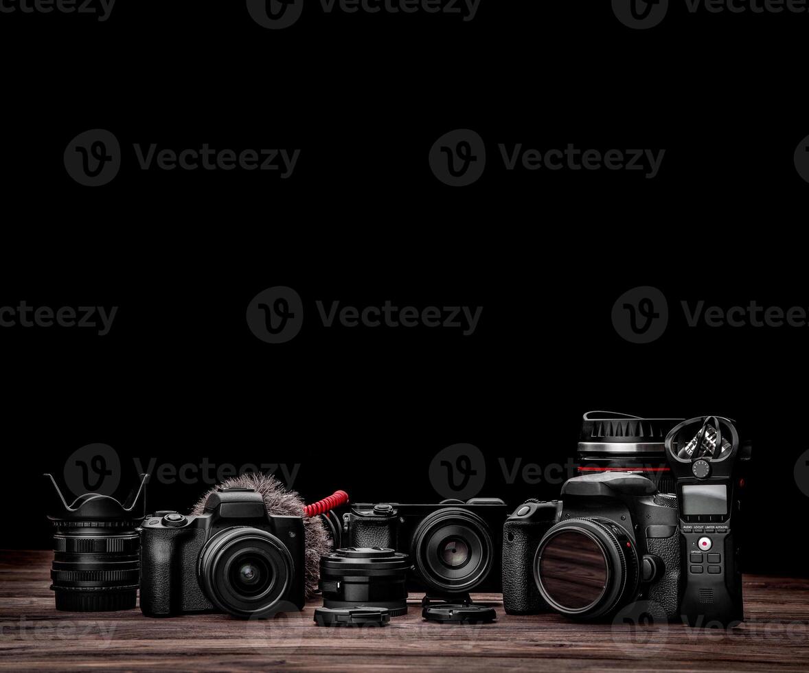 Different modern cameras and lenses on a wooden table. Technique for shooting photos and videos. blogger kit. Postcard concept for photographer and videographer.
