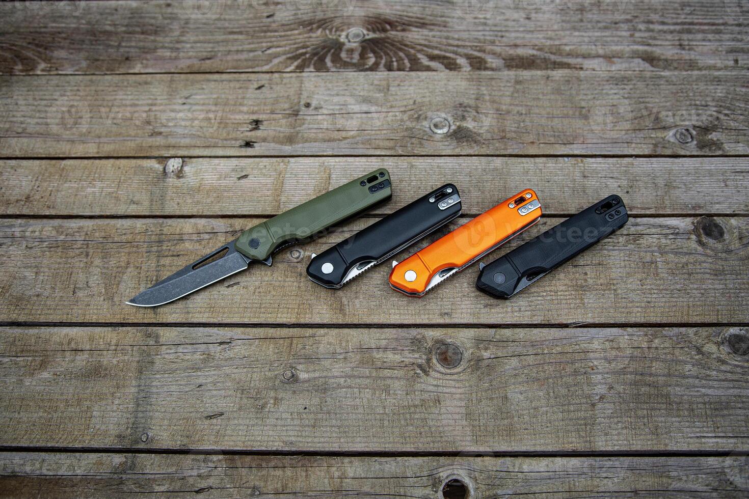 Folding penknives in different colors. Pocket knives for everyday carry. Various knives for hunting, sports and recreation. Wooden back. photo