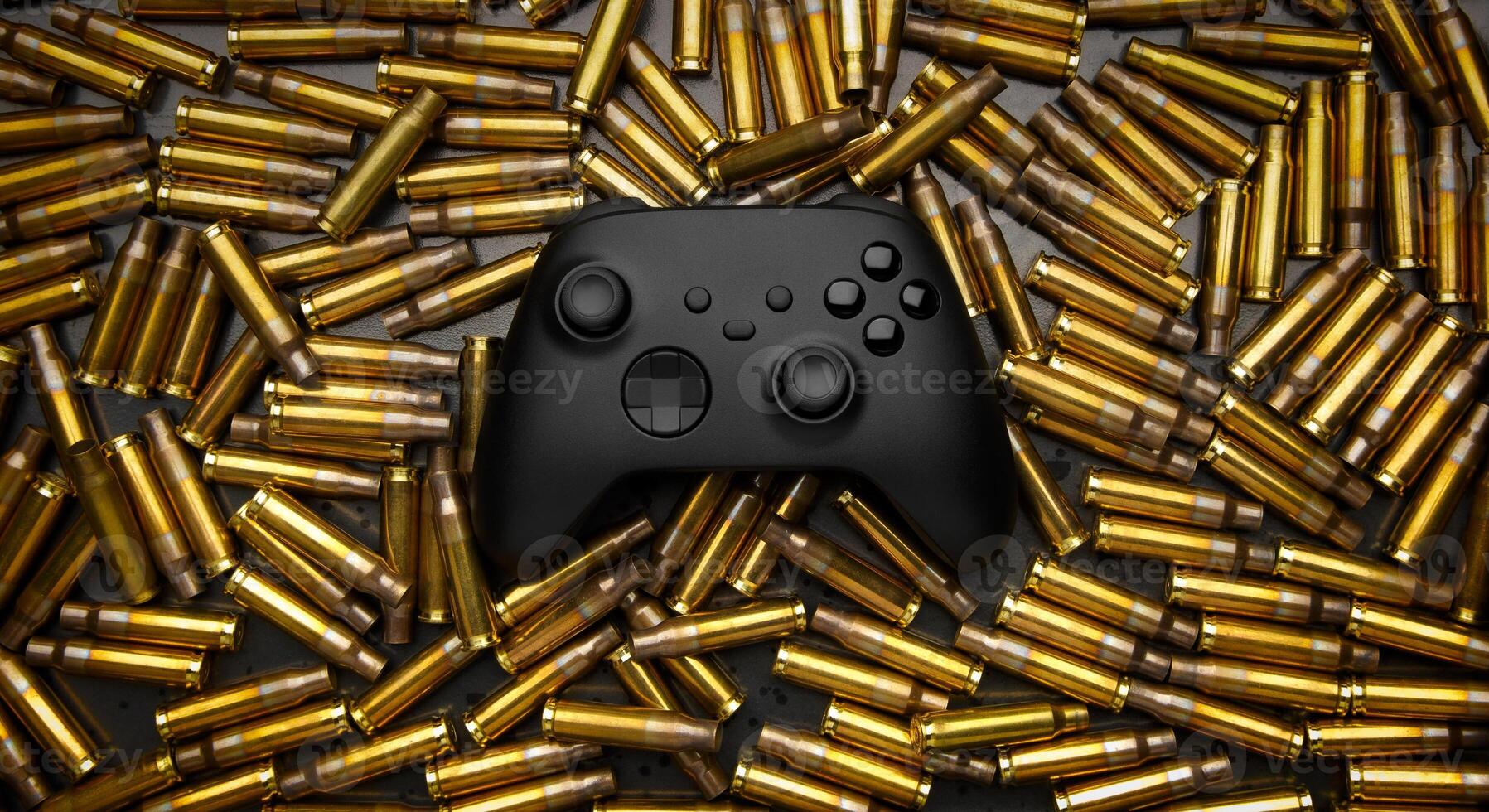Modern black gamepad on a black background among the spent cartridges. Game concept. Shooter game. photo