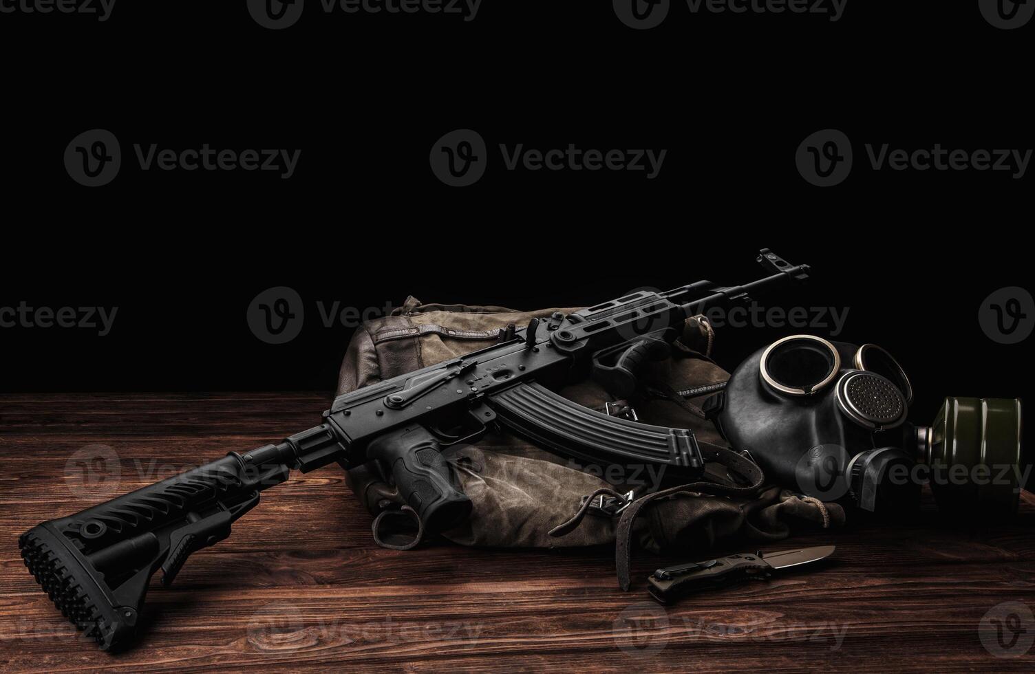 Soviet carbine in modern body kit. Weapons of Russia and the Soviet Union. Classic Soviet AK assault rifle and gas mask on a wooden back. photo