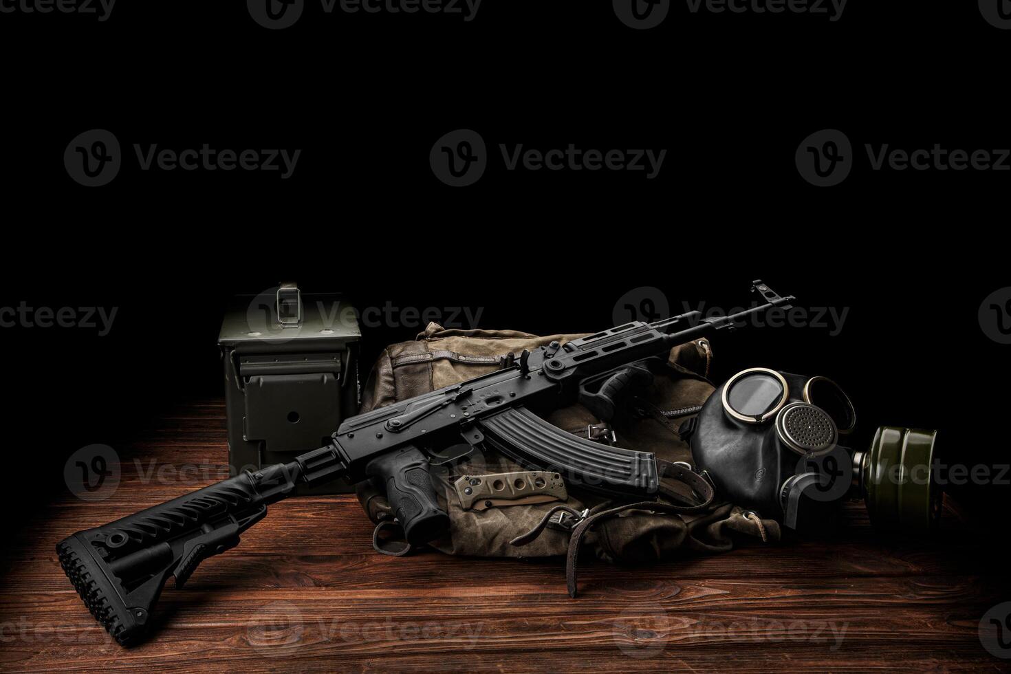 Soviet carbine in modern body kit. Weapons of Russia and the Soviet Union. Classic Soviet AK assault rifle, knife and gas mask on a wooden back. photo