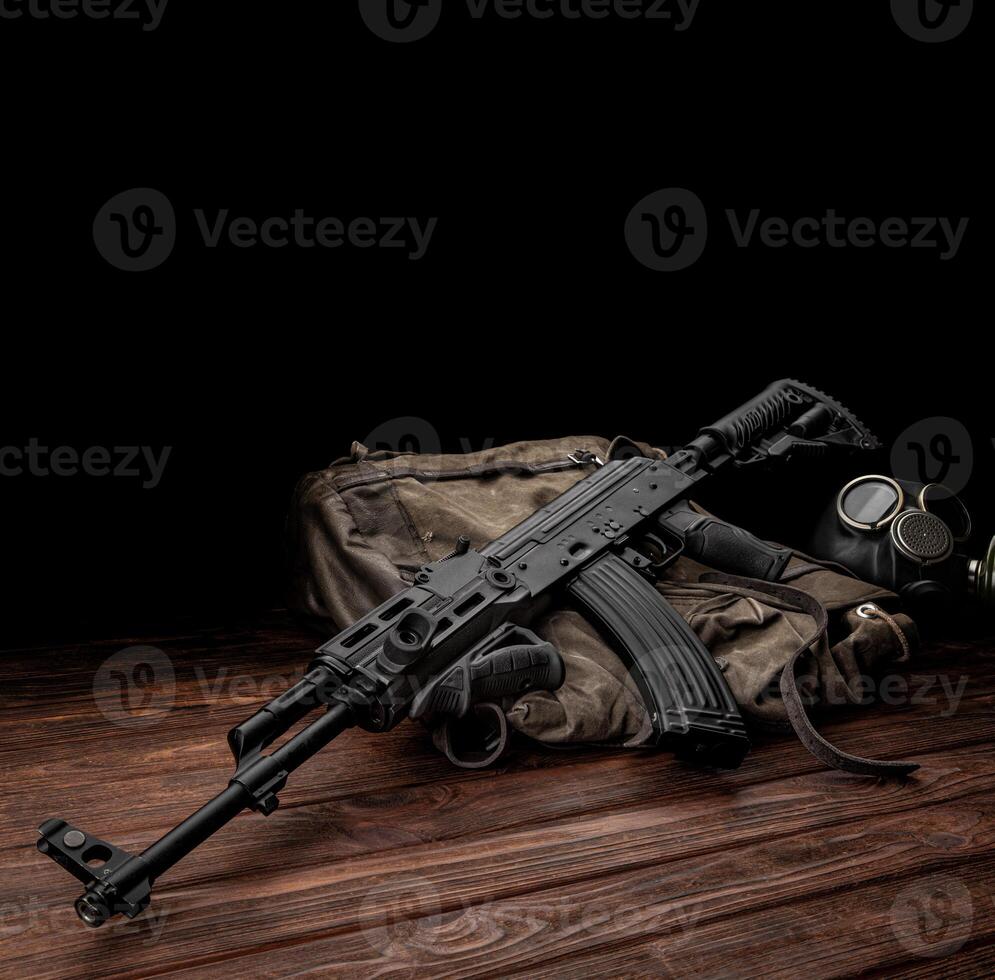 Soviet carbine in modern body kit. Weapons of Russia and the Soviet Union. Classic Soviet AK assault rifle and gas mask on a wooden back photo