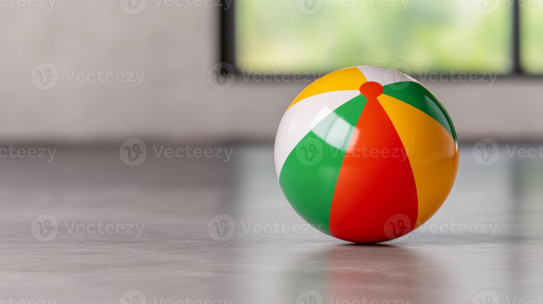 Isolated image of a deflated beach ball on a gray floor symbolizing the end of summer fun and the onset of post vacation depression photo