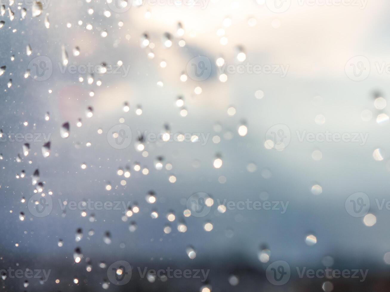 Blurred water drops of rain on blue glass with bokhe as background. Blurred rain drops on window photo