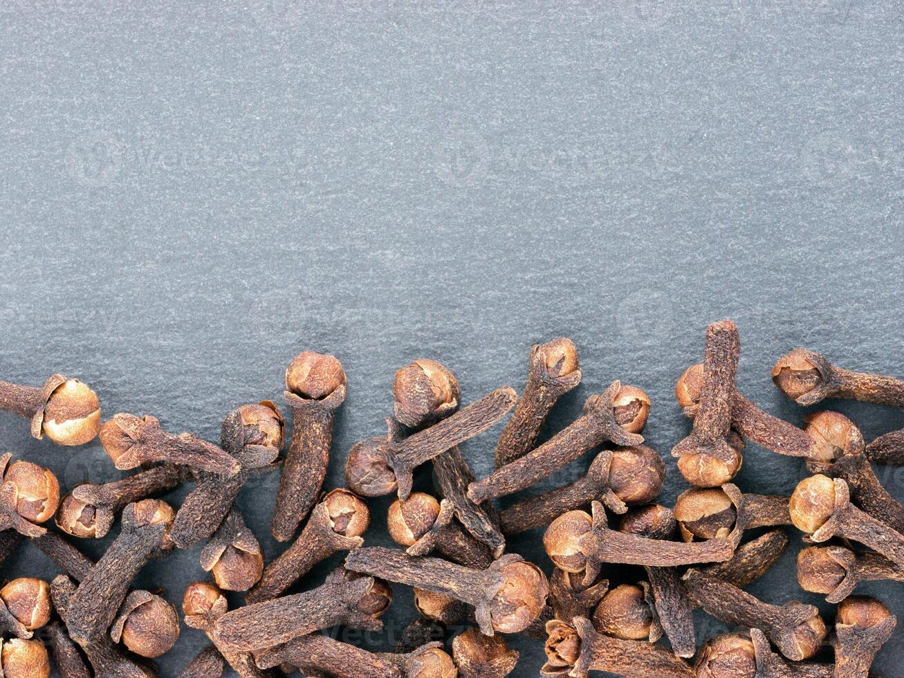 Cloves spice on gray slate background with copy space. Isolated one edge. Top view or flat lay. photo
