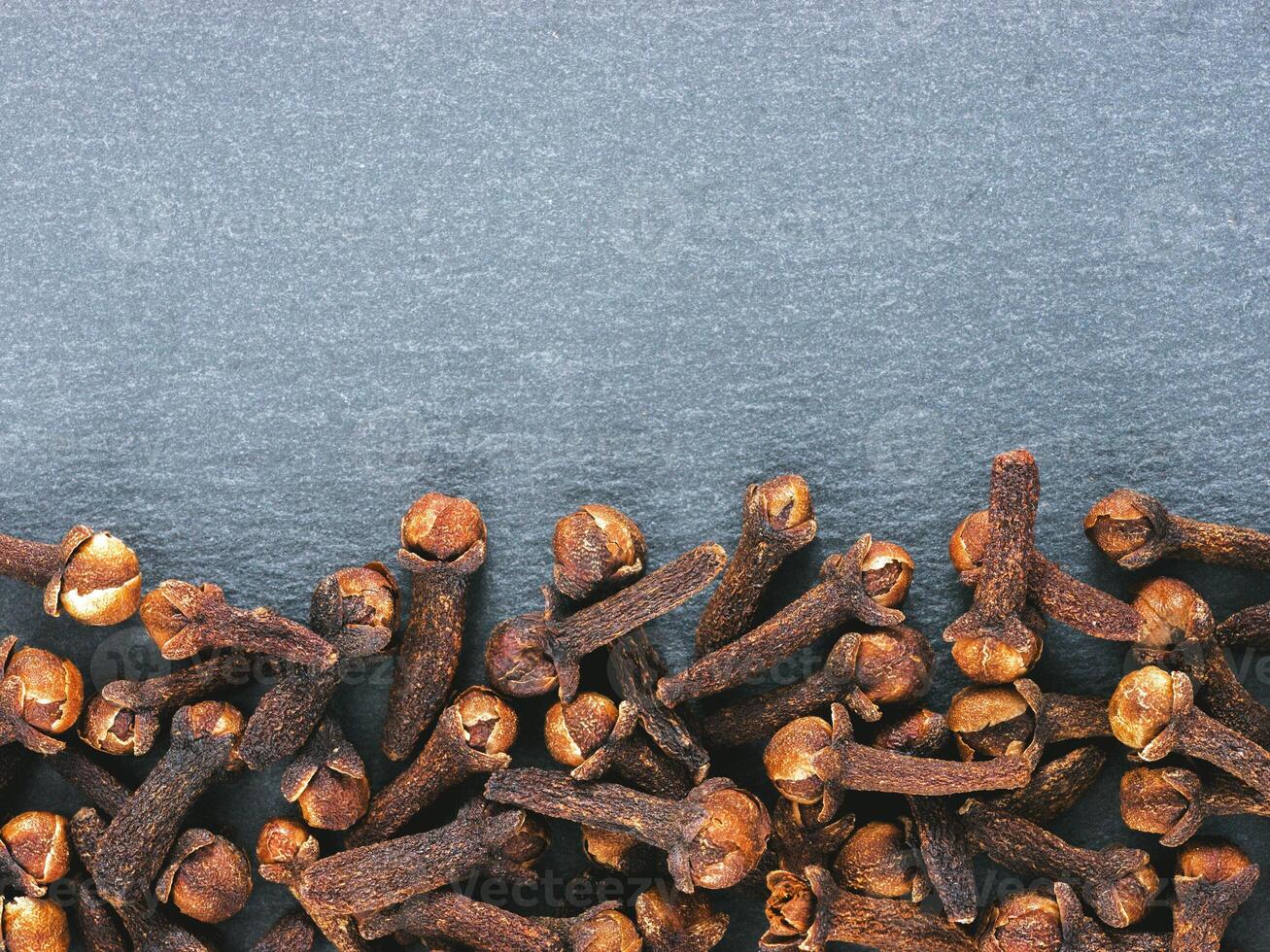 Cloves spice on gray slate background with copy space. Isolated one edge. Top view or flat lay. photo