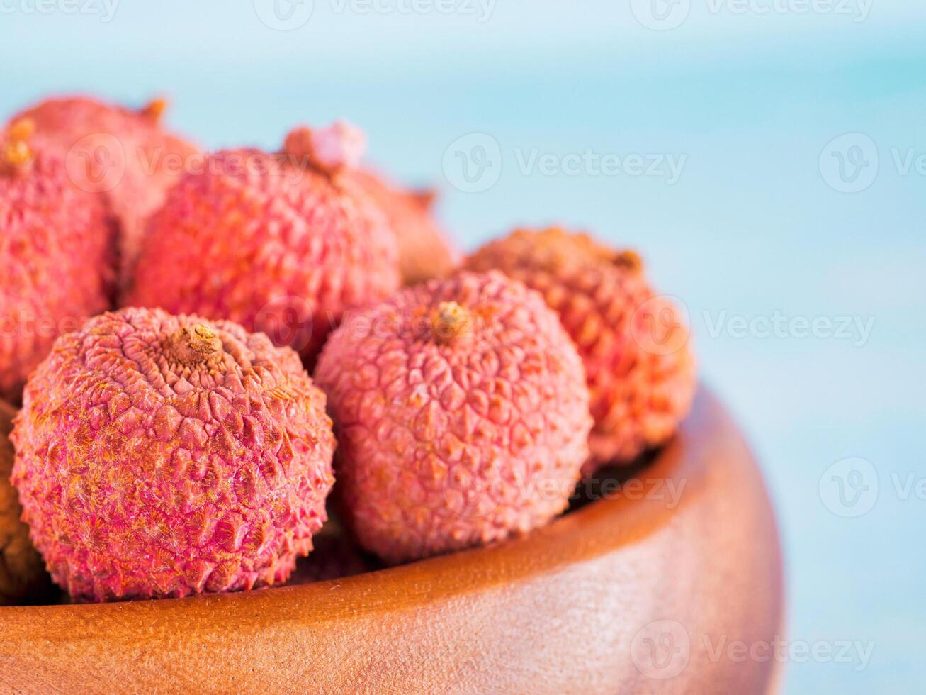 lychee fruit in clay plate on blue wooden background close up photo