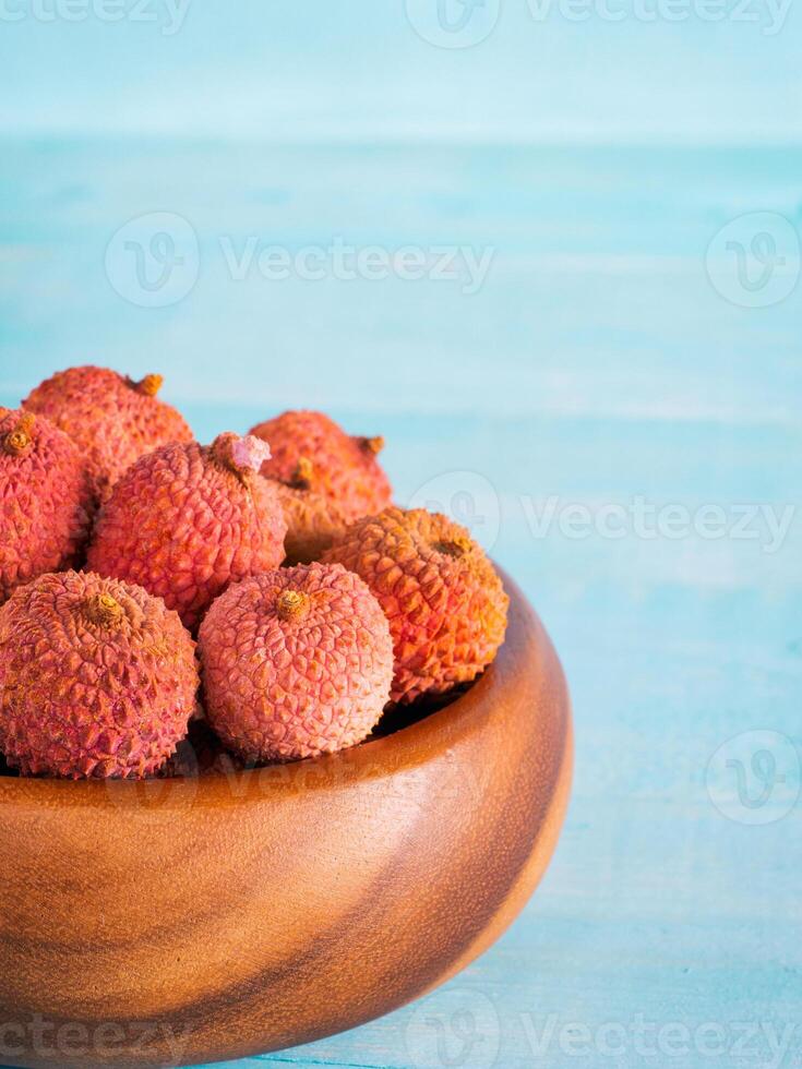 lychee fruit in clay plate on blue wooden background close up photo