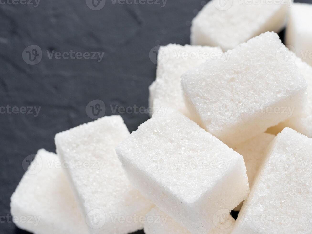 background of sugar cubes. White cube sugar on black background. White sugar close up with copy space photo