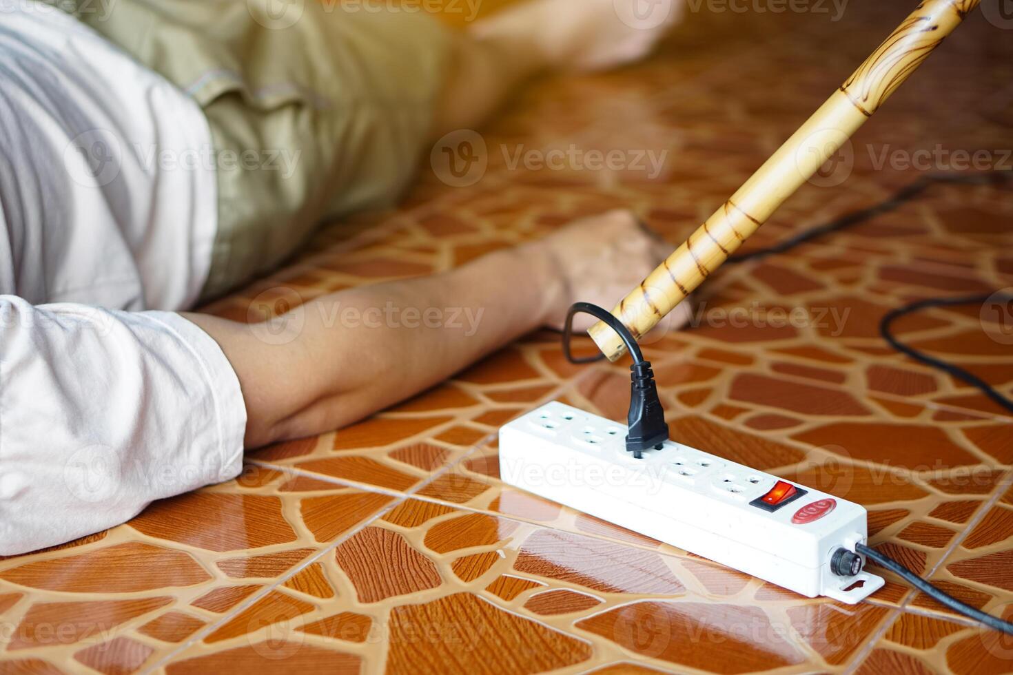 Using wooden stick is moving away the electric plug socket from the unconscious man who lay down on the floor. Concept, Electric Shock. Emergency basic rescue. First Aid photo