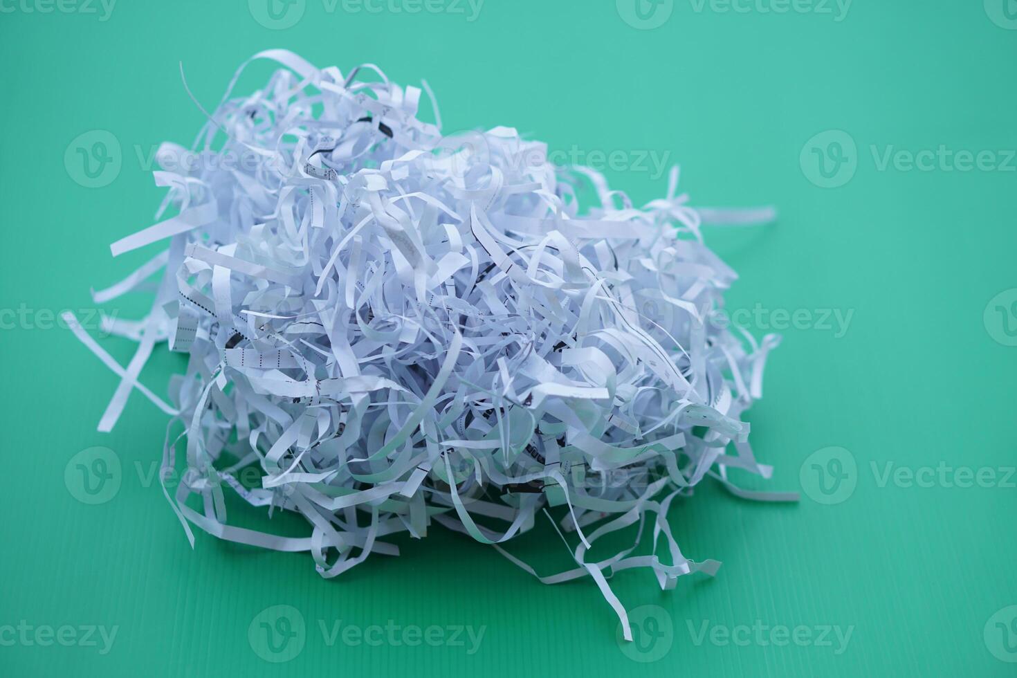 Pile of sliced used paper to be small stripes, prepare to recycle process on green background. Concept, Waste or garbage management. Documents shredded for security purposes. photo