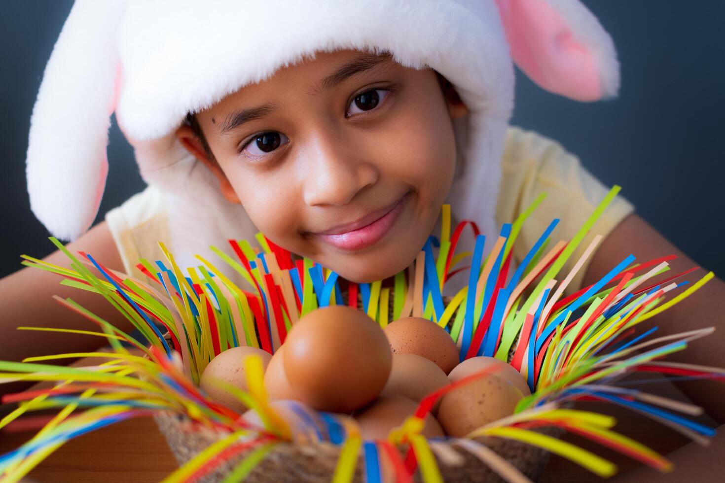 Happy easter. Close up cute girl wearing rabbit hat with chicken eggs in a basket, Easter holiday concept. photo