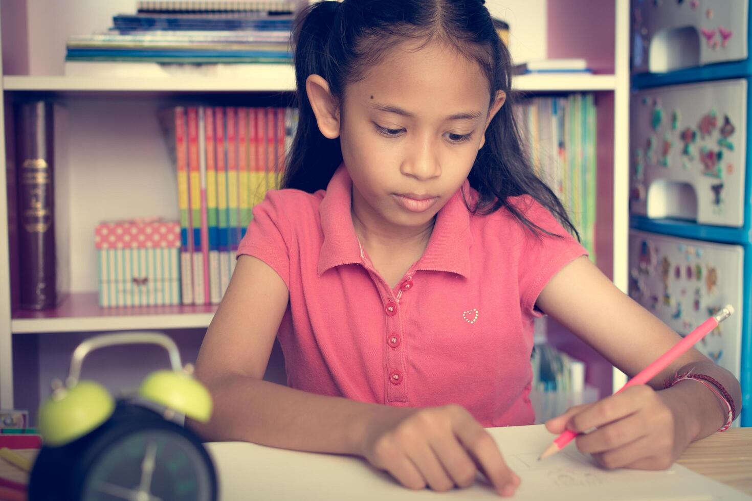Little girl drawing and writing on the desk at home. Education concept. photo
