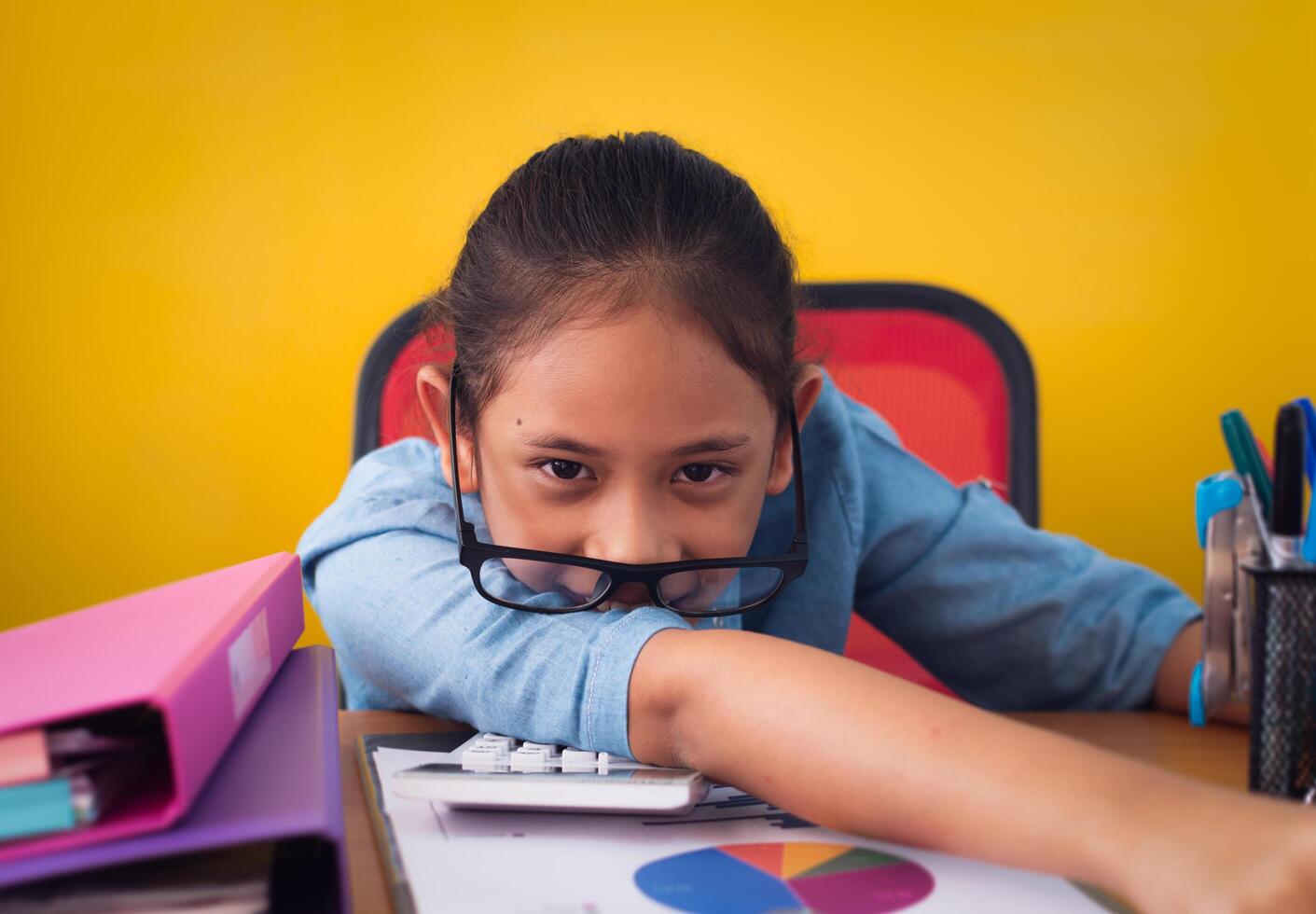 Funny cute girl working on the desk with document isolated yellow background. Concept of achievement. photo