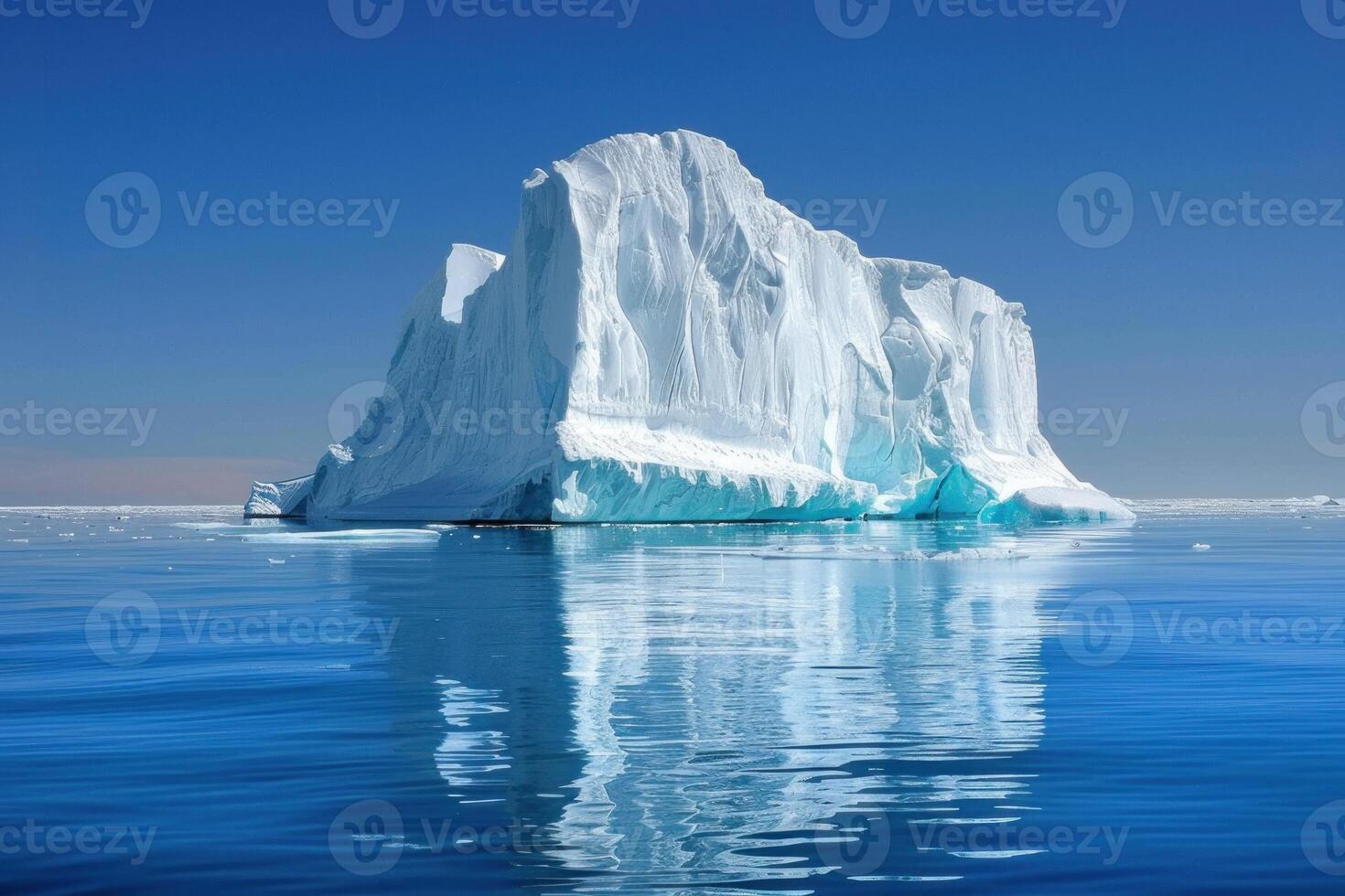 Giant iceberg floating on blue water reflecting on a sunny day photo