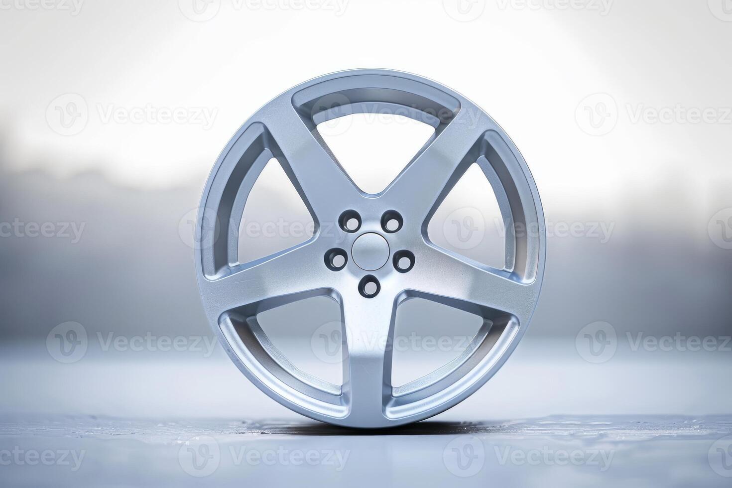 Single silver alloy wheel standing on a wet floor with a blurred background photo