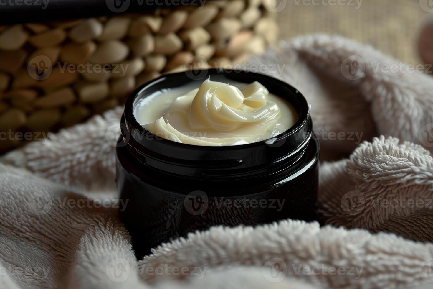 Open jar of luxurious body butter cream resting on soft towel photo