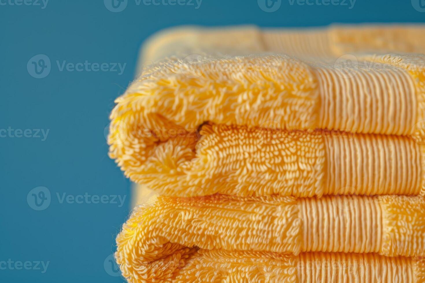 Stack of soft yellow towels folded on a blue background photo