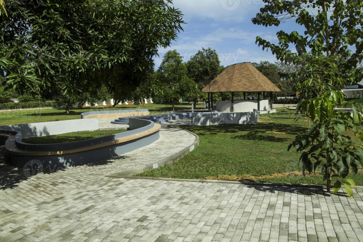 garden view with green grass and gazebo during the day with a blue background photo