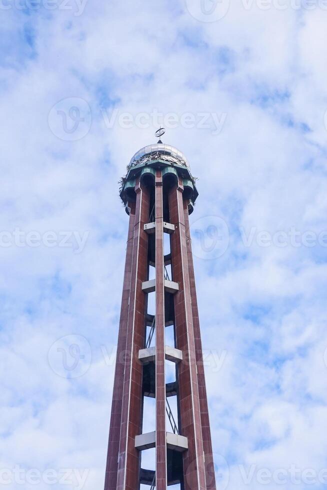 The brown mosque tower towers high against the blue sky photo