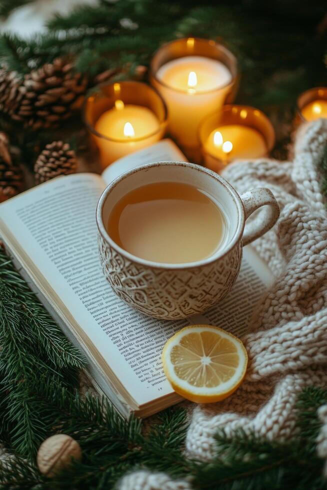 Cozy winter scene with a cup of lemon tea, a book, and a candle on a knitted blanket photo