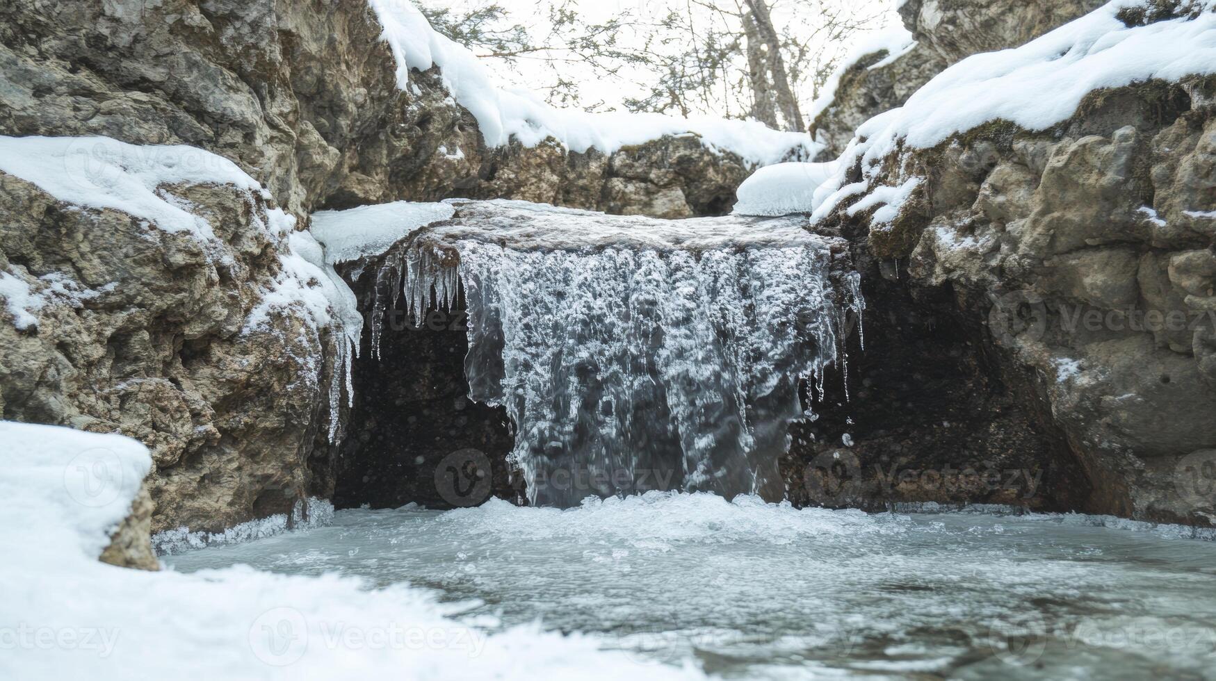 Winter waterfall cascades over icy rocks in a serene forest setting photo