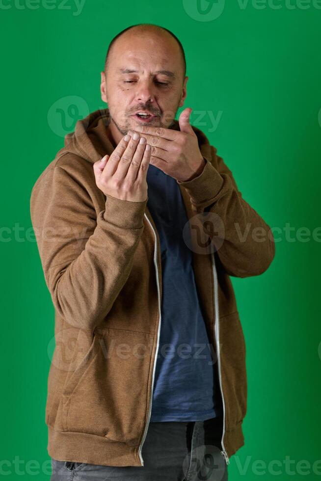 Middle aged bald man demonstrating composition techniques with hand gestures against a green studio backdrop. photo