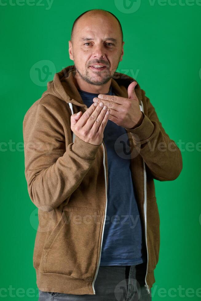 Middle aged bald man demonstrating composition techniques with hand gestures against a green studio backdrop. photo