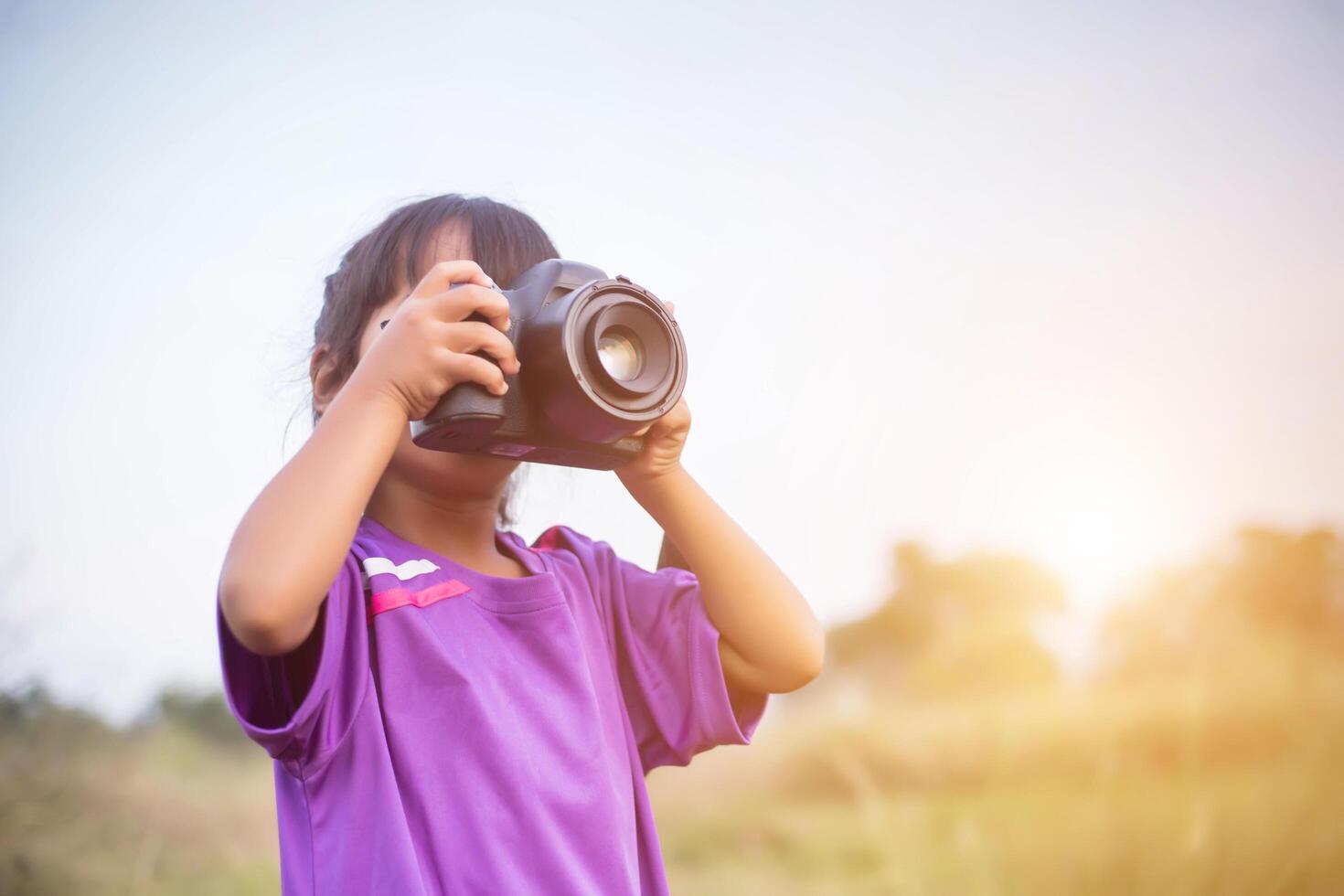 Woman with camera hiding behind the tree photo